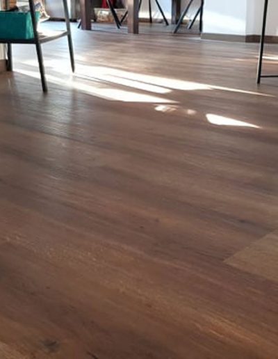 Vinylboden in Holz-Parkettoptik und ein Ausschnitt eines Wohnzimmers