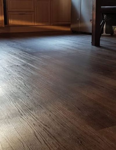 Vinylboden in Holz-Parkettoptik und ein Ausschnitt eines Wohnzimmers mit Möbel